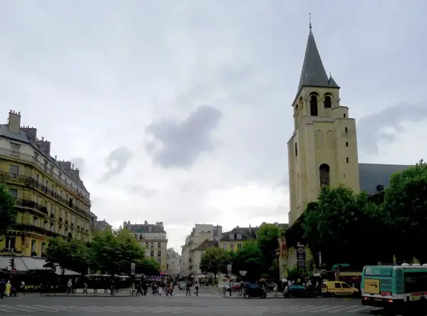 Wieża kościoła Saint-Germain-des-Prés na tle paryskiej ulicy z budynkami i przechodniami.