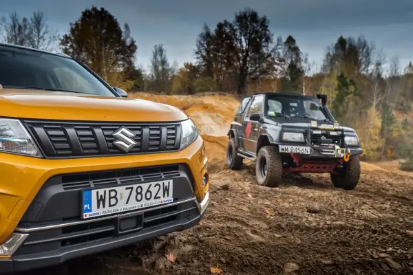Żółty Suzuki Vitara 2025 i czarny, terenowy model na piaszczystym podjeździe.