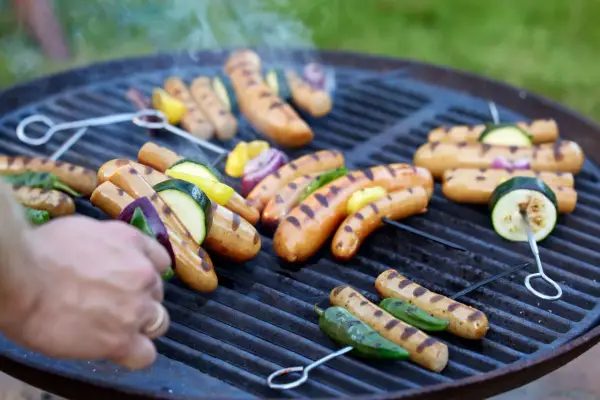 Grilla korv med grönsaker på en kolgrill. Röken stiger och ger en härlig doft.