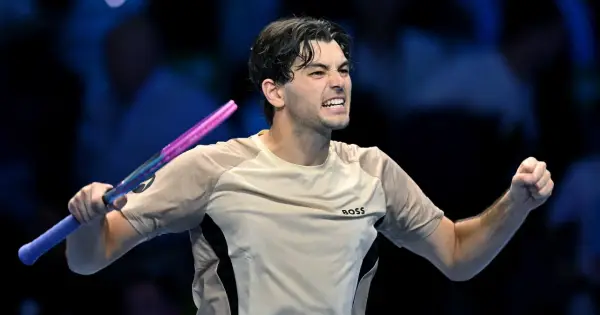 Taylor Fritz, tenisista, triumfuje po wygranym punkcie, zaciskając pięść i unosząc rakietę.