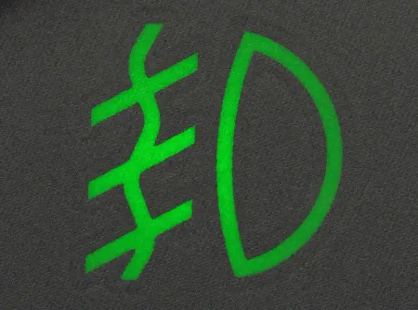 Zielony symbol przeciwmgielny na ciemnym tle.