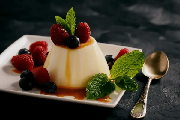 Panna cotta z malinami i borówkami, polana syropem. Idealny deser, gdy szukasz prostego panna cotta przepis.