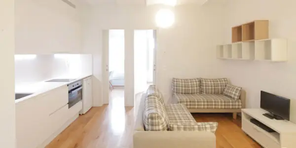 Cocina y salón modernos en la residencia Unihabit Sant Cugat. Sofás a cuadros y estanterías flotantes.