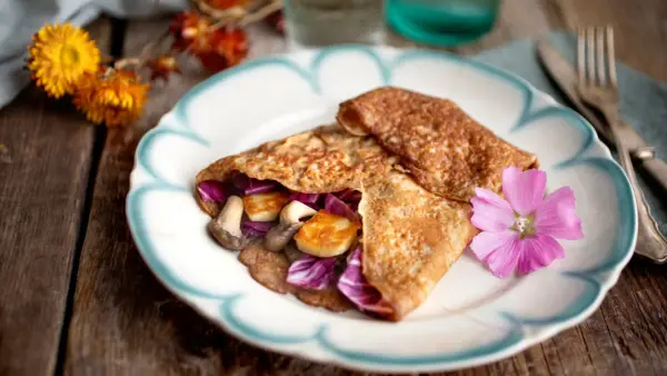 Matiga pannkakor fyllda med svamp, halloumi och rödkål, dekorerade med en rosa blomma.