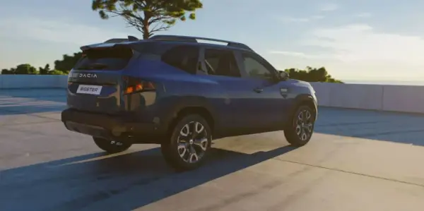 Niebieski Dacia Bigster na tle nieba i drzewa. Zbliżają się jego wymiary.