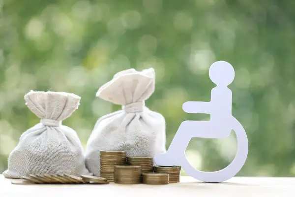 Pieniądze i symbol osoby na wózku inwalidzkim. Zastanawiasz się, ile wynosi świadczenie wspierające?