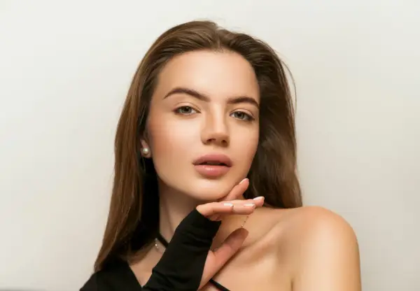 Delikatny makijaż nude podkreśla naturalne piękno młodej kobiety. Jej skóra lśni subtelnym blaskiem, a usta kuszą delikatnym kolorem.