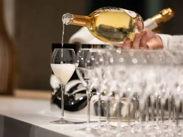 Ein Glas wird mit prickelndem Vranken Pommery gefüllt, daneben stehen weitere Champagnergläser bereit.