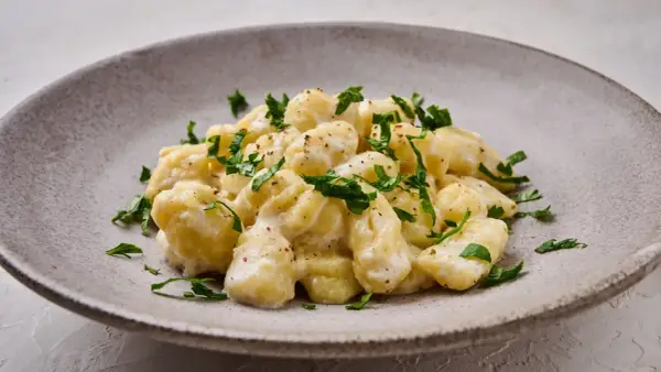 Puszyste gnocchi z serem, polane kremowym sosem i posypane świeżą natką pietruszki. Idealne danie dla miłośników włoskich smaków.