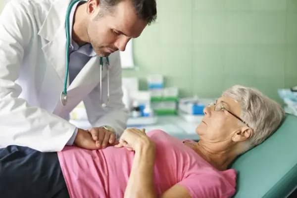 Lekarz bada pacjentkę, która skarży się na przelewanie w brzuchu. Delikatnie dotyka jej brzucha, próbując zdiagnozować przyczynę dolegliwości.