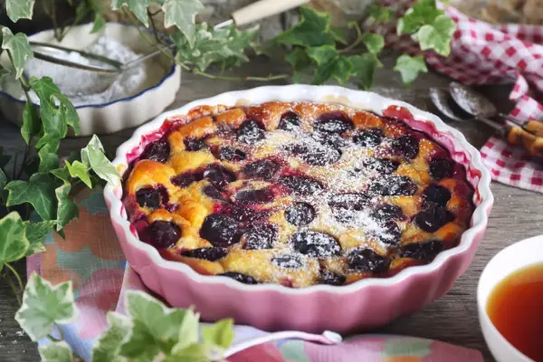 Un délicieux clafoutis aux prunes, saupoudré de sucre glace, prêt à être dégusté.