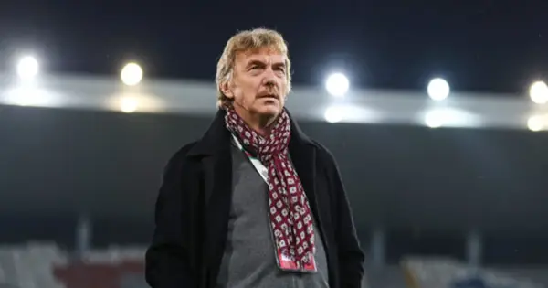 Zbigniew Boniek w płaszczu i szaliku na tle stadionu.