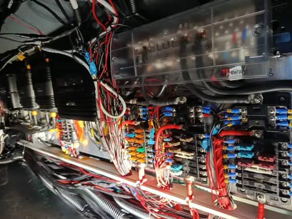 Skomplikowana instalacja elektryczna na jachcie, z widocznymi bezpiecznikami, przewodami i skrzynką "Blue Sea Systems".