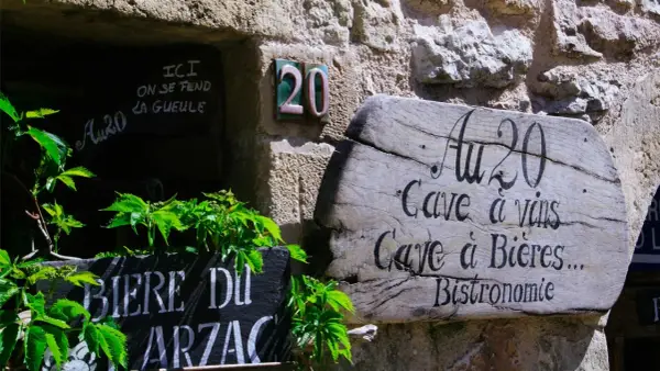 Bonjour! Drewniany szyld "Au 20" zaprasza do piwnicy z winami i piwami. Obok tablica z napisem "Biere du Arzac".