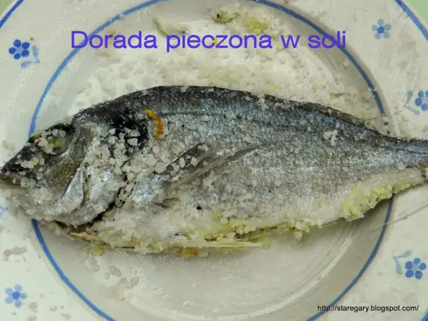 Dorada pieczona w soli, cała ryba pokryta grubą warstwą soli, gotowa do pieczenia.