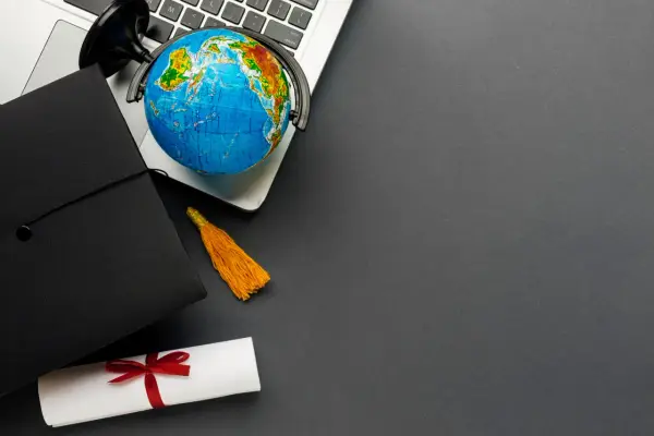Dyplom, czapka absolwenta i globus na laptopie symbolizują globalne wykształcenie i nostryfikację.