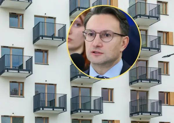 Mężczyzna w okularach przemawia na tle nowoczesnego bloku z balkonami, dyskutując o problemach najmu krótkoterminowego.
