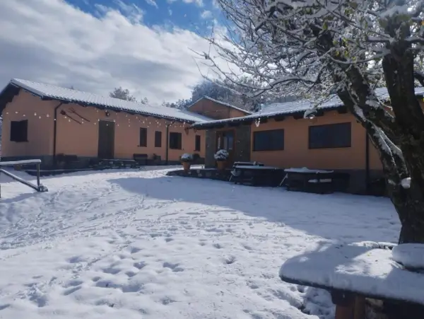 Agriturismo Acqua Bianca imbiancato dalla neve. Un paesaggio invernale incantevole con edifici color pesca e un cielo azzurro con nuvole bianche.