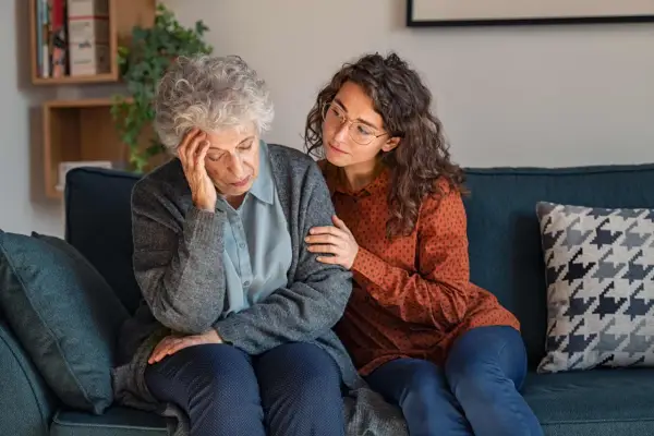 Una giovane donna conforta un'anziana con Alzheimer, mostrando quando ricoverare un malato di Alzheimer.