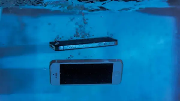 Dwa smartfony, jeden srebrny, drugi czarny, zanurzają się w wodzie. Ten wodoodporny smartfon przetrwa nawet takie zanurzenie.