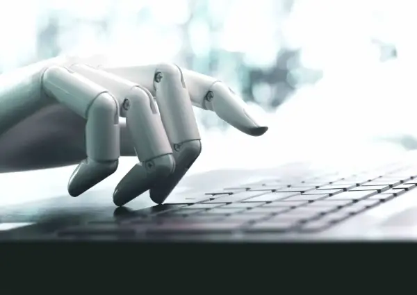 Mano robótica escribiendo en un teclado, una imagen que ilustra qué son los bots y su interacción con la tecnología.
