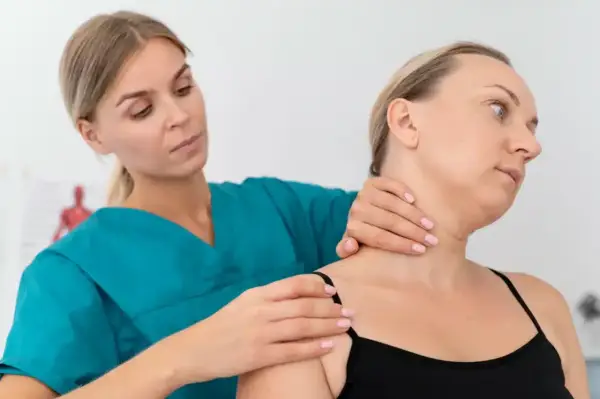 Fizjoterapeuta bada szyję pacjentki, oceniając potencjalne objawy chorobowe kręgosłupa szyjnego.