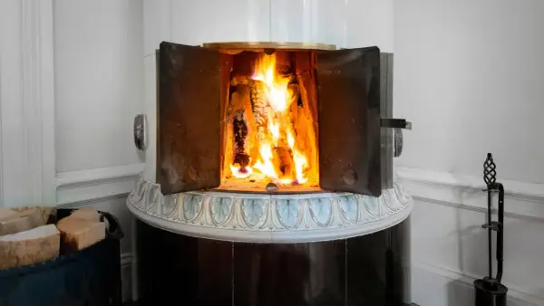 En öppen kamin med flammande ved. Det kan vara farligt att elda i kamin om man inte är försiktig.