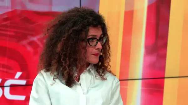 Aleksandra Pawlicka, z burzą kręconych włosów i okularami, opowiada o swoich dzieciach na tle kolorowego studia.