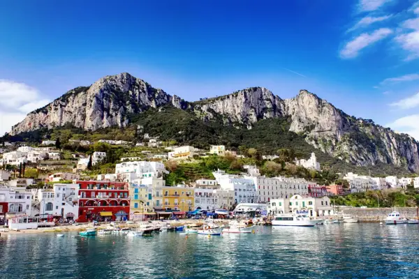 Kolorowe domy nad zatoką, góry w tle. Widok na urokliwy port na wyspie Capri.