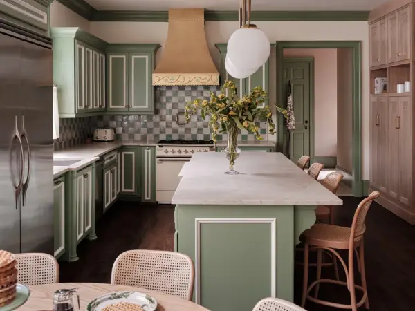 Elegantes cocinas verdes con gabinetes de madera clara, encimeras de mármol y un toque de color en la campana de la estufa.
