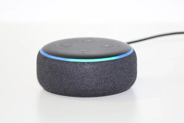 Ein grauer Echo Dot mit leuchtendem Ring, bereit, Alexa Skills zu aktivieren und dein Zuhause zu steuern.