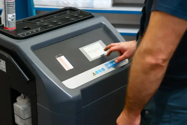 Mechanik dotyka ekranu maszyny do adaptacji skrzyni biegów, przygotowując ją do czyszczenia.