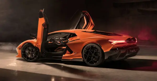 Pomarańczowy Lamborghini Revuelto z otwartymi drzwiami, ukazujący sportowe wnętrze i agresywną sylwetkę.