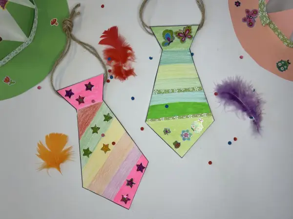 Bunte Krawatten basteln mit Federn und Stickern. Eine pinke und eine grüne Krawatte, dekoriert mit Sternen und Schmetterlingen.