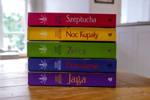 Pięć kolorowych książek Katarzyny Bereniki Miszczuk ułożonych jedna na drugiej. Na okładkach widnieje symbol kwiatu paproci.