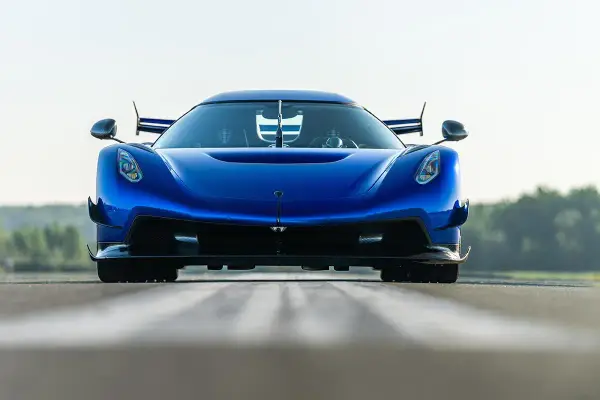 Niebieski Koenigsegg Jesko Attack z agresywnym przednim splitterem i spojlerami, gotowy do ataku na torze.