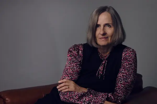 Susanna Alakoski, en svensk författare, sitter på en brun soffa med armarna korslagda.