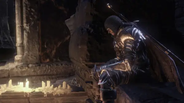 Rycerz w zbroi siedzi przy świecach, szukając wskazówek w mrocznym świecie. To może być kluczowy moment w twoim **dark souls poradnik**.
