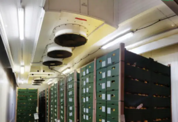 Almacén con cajas apiladas y ventiladores en el techo para el sistema de refrigerante CO2.