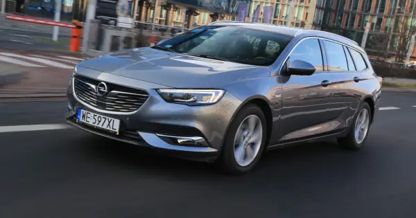 Szary Opel Insignia 2.0 CDTI w wersji kombi jedzie po miejskiej drodze.