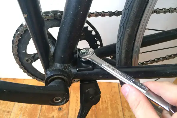 Montaż stopki rowerowej. Klucz dokręca śrubę mocującą stopkę do ramy roweru.
