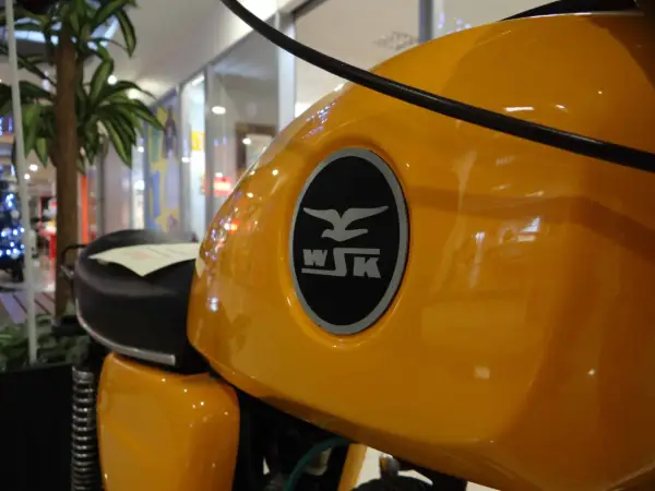 Żółty bak motocykla WSK 125 z charakterystycznym logo. Ile koni kryje się pod tą błyszczącą karoserią?