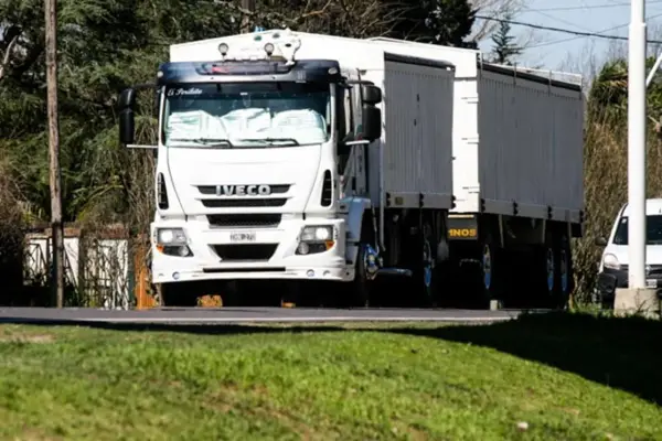Biała ciężarówka Iveco z naczepą jedzie drogą. Kierowca ciężarówek wyrusza w długą trasę.