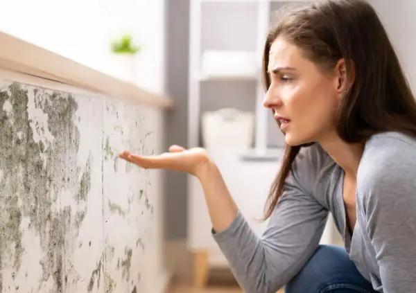 Donna preoccupata osserva muffa su muro, cercando soluzioni su come eliminare umidità in casa.