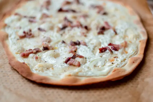 Flamenkuche maison, une recette facile pour un repas gourmand. Pâte fine, crème, lardons et oignons pour une tarte flambée parfaite.