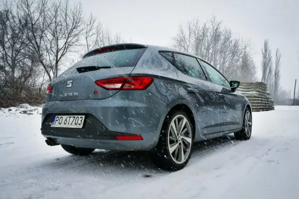 Szary Seat Leon FR w zimowej scenerii, pokryty śniegiem.