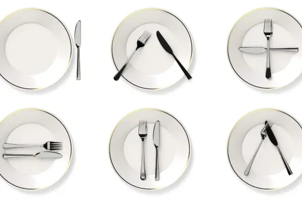 Six assiettes blanches avec des couverts disposés de différentes manières, illustrant la position des couverts signification.