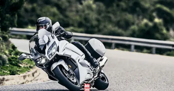 Motocyklista w białym Yamaha FJR 1300 na zakręcie drogi.