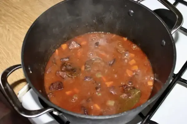 Gorący gulasz z dzika po myśliwsku bulgocze w garnku. Aromatyczny sos z kawałkami mięsa i warzyw.