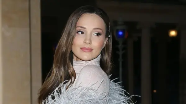 Elegancka żona Szczęsnego w błyszczącej sukni z piórami, z delikatnym makijażem i perłową spinką we włosach.